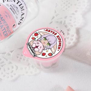 Puede incluir: Un recipiente de pl&aacute;stico rosa y blanco con un personaje de dibujos animados en la tapa. El personaje es un zorro rosa con pelaje blanco y ojos verdes. El recipiente tiene el texto "ABYSS KITCHEN" y "Strawberry" en la tapa.