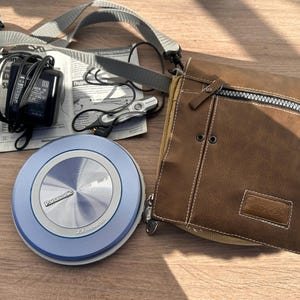 May include: A white ceramic mug with a black handle and the text "But First, Coffee" in a bold, black font. The mug is set against a blurred background, suggesting a cozy setting.