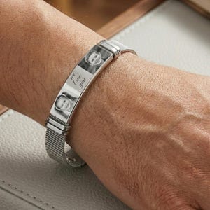 Könnte beinhalten: Ein silbernes Armband mit einem Mesh-Armband und einem rechteckigen Mittelstück. Das Mittelstück zeigt zwei Schwarz-Weiß-Fotos und die Worte "we love you". Das Armband wird am Handgelenk getragen.