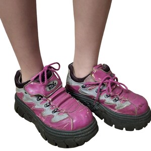 May include: A pair of pink and gray platform sneakers with black soles. The sneakers have a chunky design, pink laces, and the brand name "ROXY" is visible on the side. The shoes show signs of wear.