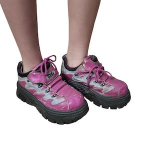 May include: A pair of pink and silver Roxy platform sneakers. The sneakers have a chunky black sole, pink laces, and the Roxy logo on the side. The shoes show signs of wear.