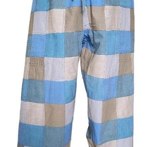 May include: Patchwork trousers in a blue, beige, and white colour scheme. The trousers have a drawstring waist and a wide-leg design. The fabric is a patchwork of squares in various shades of blue, beige, and white.