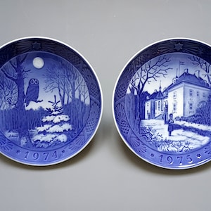 Puede incluir: Dos platos decorativos azules y blancos. Uno presenta un b&uacute;ho en una escena de bosque con luna llena y el a&ntilde;o 1974. El otro representa un edificio y el a&ntilde;o 1975.