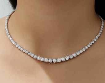 May include: A delicate necklace featuring a series of round, sparkling gemstones. The necklace is set in a silver or white metal and rests gracefully on the neckline. The gemstones are evenly spaced, creating a continuous line of brilliance.