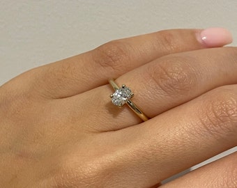 May include: A gold band ring with a single oval-shaped diamond.