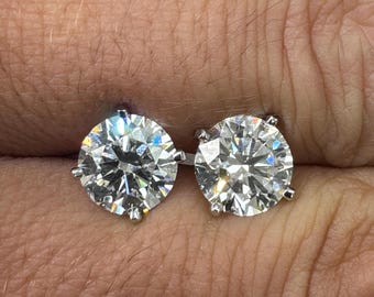 Könnte beinhalten: Ein Paar runde, klare Diamant-Ohrringe, die in einer silbernen Metallfassung gefasst sind.