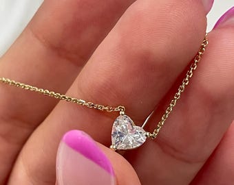 Può includere: Una collana con catena d'oro con un ciondolo a forma di cuore di diamante.