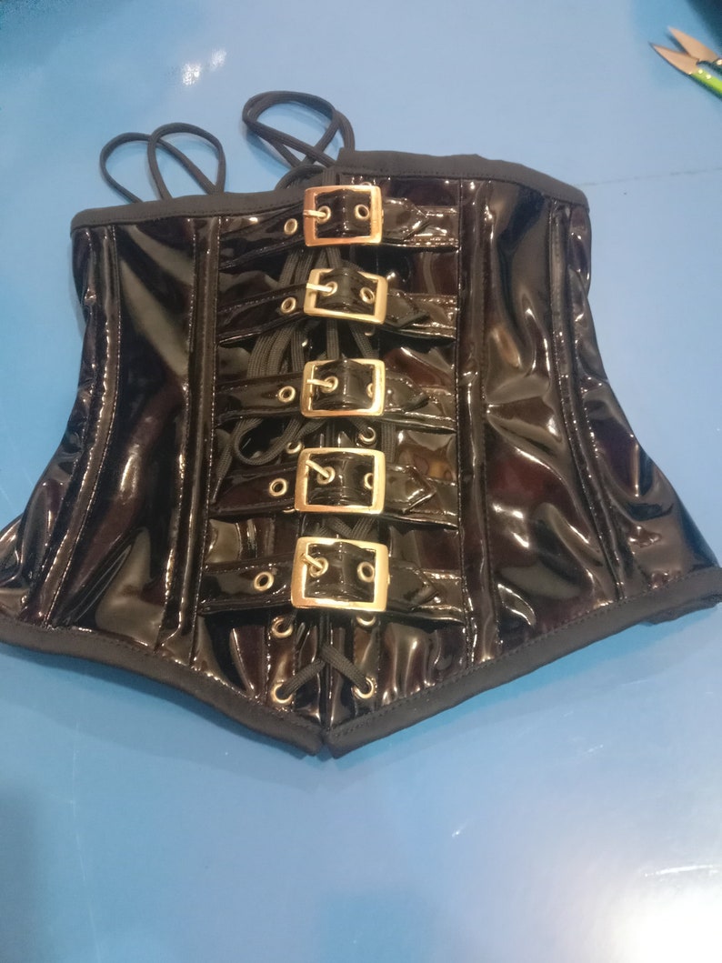 May include: Black patent leather corset with gold-toned buckles and lace-up front.