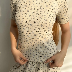 Peut inclure: Un haut blanc à manches courtes avec un petit imprimé floral. Le haut est fait d'un tissu doux et extensible et a une coupe décontractée.