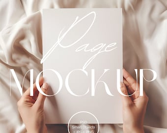 May include: A white page mockup held by hands against a white satin background. The text "Page Mockup" is written in white on the page. The text "PSD Smart Objects .JPG .PNG" is written in white at the bottom of the page.