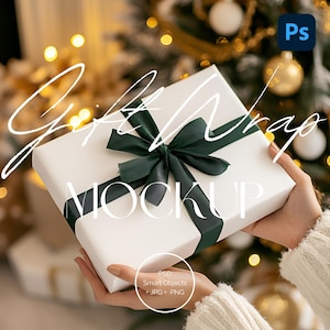 May include: A white gift box with a green satin ribbon and bow. The box is being held by a person's hands. The text "Gift Wrap Mockup" is written in white on the box.