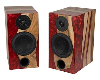 May include: A pair of wooden speaker cabinets with red and brown wood grain patterns. Each speaker has two black drivers, one large and one small.
