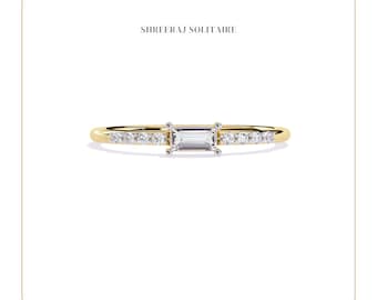 May include: A gold band ring with a rectangular-shaped diamond and smaller diamonds set along the band. The ring is on a white background. SHREERAJ SOLITAIRE is written above and below the ring.