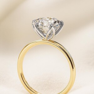 Profile view of a high-set round stone on a 14k gold solitaire engagement ring, minimal prong setting, elegant.
