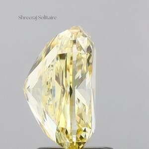 May include: A radiant, yellow-hued diamond with a unique cut. The gemstone is faceted, reflecting light and showcasing its clarity. The text "Shreeraj Solitaire" is visible in the upper left corner. The diamond's shape is elongated, with a pointed tip.