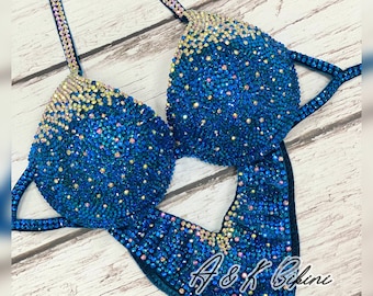 May include: A blue and gold sequined competition bikini with the text "A & K Bikini" on the bottom.
