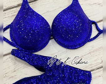 Puede incluir: Un bikini azul real con un top halter y una parte inferior de corte alto. El bikini está completamente cubierto de pedrería.