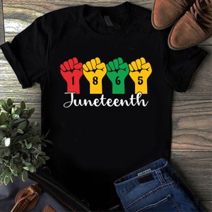 May include: Black t-shirt with a graphic of raised fists forming the year 1865 and the word "Juneteenth" below.