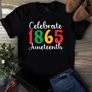 以下が含まれることがあります： 黒のTシャツに「Celebrate 1865 Juneteenth」という文字が赤、黄、緑で書かれています。