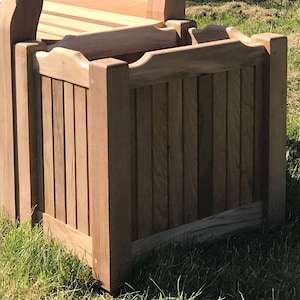 May include: A wooden planter box with vertical slats and a slightly curved top edge. The planter is made of natural wood with a light brown colour.
