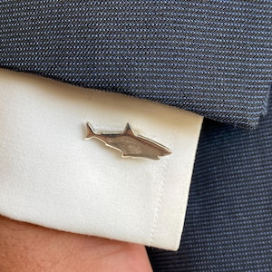May include: Silver shark cufflinks. The cufflinks are shaped like a shark and are a great way to add a touch of personality to your outfit.