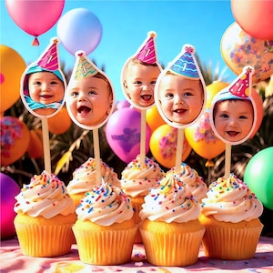 May include: Six cupcakes with white icing and colourful sprinkles topped with a wooden stick and a round photo of a baby wearing a birthday hat. The cupcakes are on a table with colourful balloons in the background.