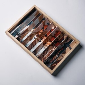 May include: A wooden photo display featuring multiple images arranged in a fan-like pattern. The photos depict various people, with a warm color palette. The display is rectangular and sits on a white surface.