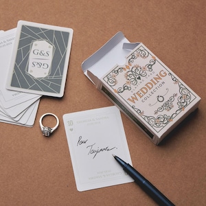 Puede incluir: Un juego de cartas de boda con una caja decorativa, un anillo de diamantes y una tarjeta firmada. Las cartas tienen un diseño geométrico en el reverso. La caja dice "Wedding Collection".