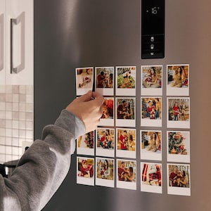 Peut inclure: Plusieurs photos carrées aimantées sont fixées sur une porte de réfrigérateur en acier inoxydable. Les photos représentent des personnes et des scènes. Une main place un aimant photo sur la porte.