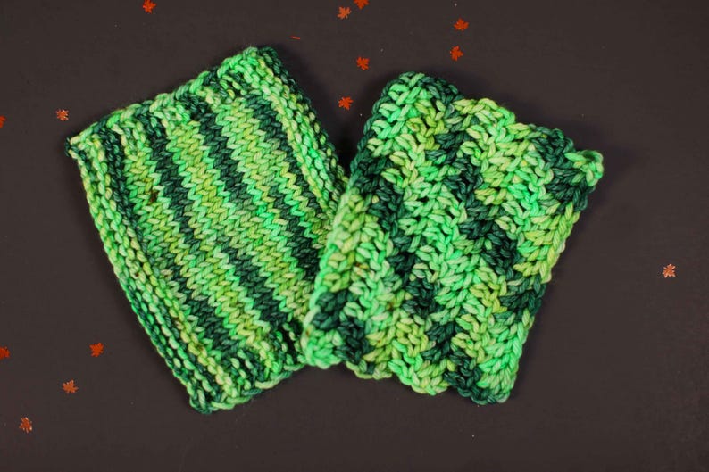 May include: Two green and black striped knitted dishcloths. The dishcloths are made of a soft, textured yarn.