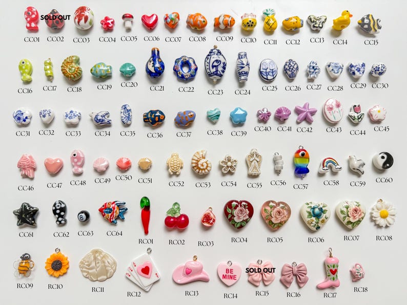 K&ouml;nnte beinhalten: Eine Sammlung kleiner Anh&auml;nger aus Keramik und Harz, die in Reihen angeordnet sind und verschiedene Formen wie Tiere, Blumen, Herzen, Lebensmittel und Symbole aufweisen, jeweils mit einem eindeutigen alphanumerischen Code zur Identifizierung.