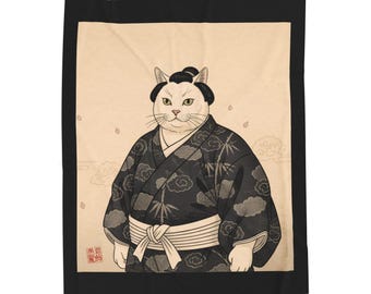 May include: A white cat wearing a black kimono with cloud patterns and a white obi. The cat has a traditional Japanese hairstyle. The background is beige with faint clouds and cherry blossom petals. The blanket has a black border.