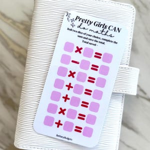 May include: A white, textured planner with a card that reads "Pretty Girls CAN do maths." The card features pink squares and mathematical symbols. The text on the card encourages the user to roll dice and save the total. The planner has a snap closure.