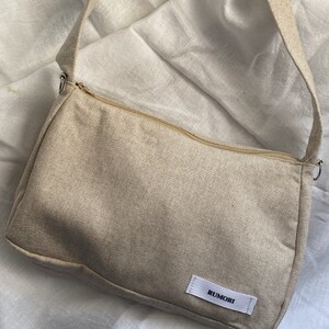 Borsetta da spalla in tela 100% cotone.
La borsa è completa di zip per la chiusura e di ganci per attaccare catenine decorative