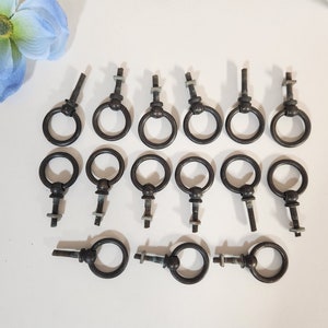 May include: A set of 15 black metal ring pulls with a screw back. The pulls are all the same size and shape, and they have a slightly distressed finish.