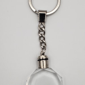May include: A silver keychain with a clear crystal charm. The charm is shaped like a faceted octagon.