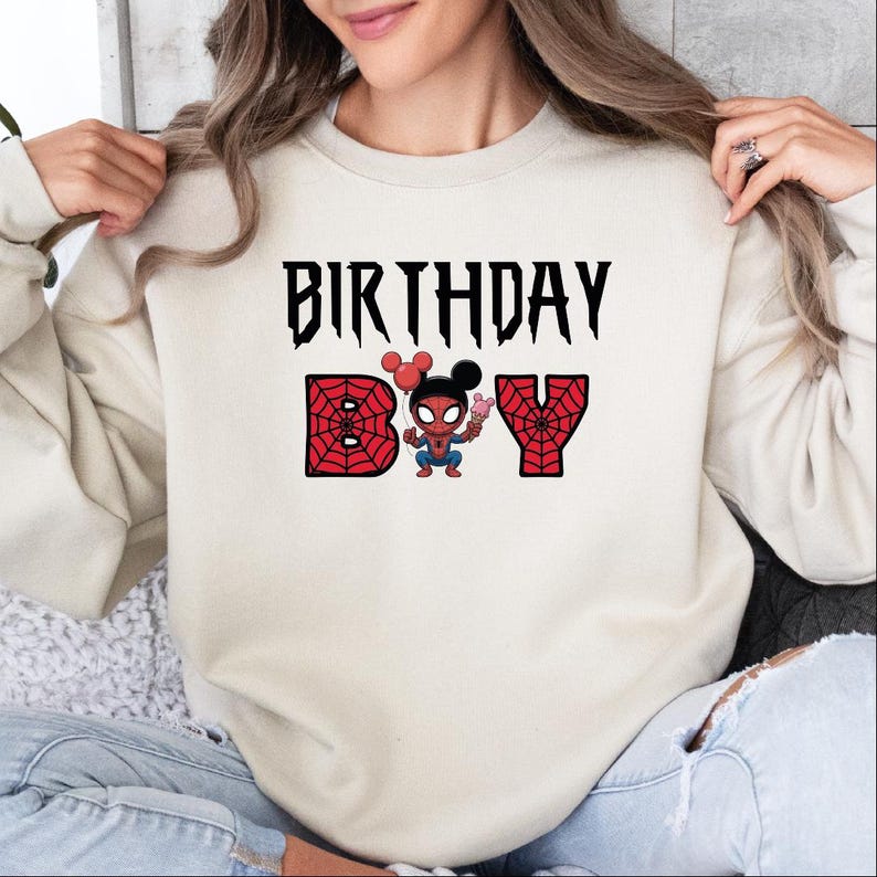 A woman wearing a white sweatshirt with the text "BIRTHDAY BOY" printed on it, along with a Spider-Man character.