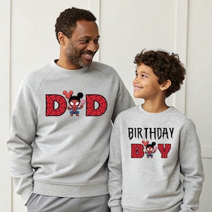 A man and a young boy wearing matching gray sweatshirts with Spider-Man and birthday text printed on them.