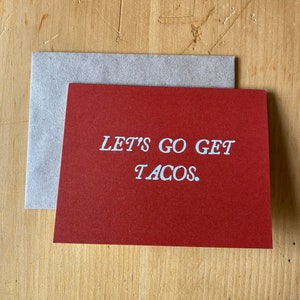 May include: A red card with white text that reads "LET'S GO GET TACOS."