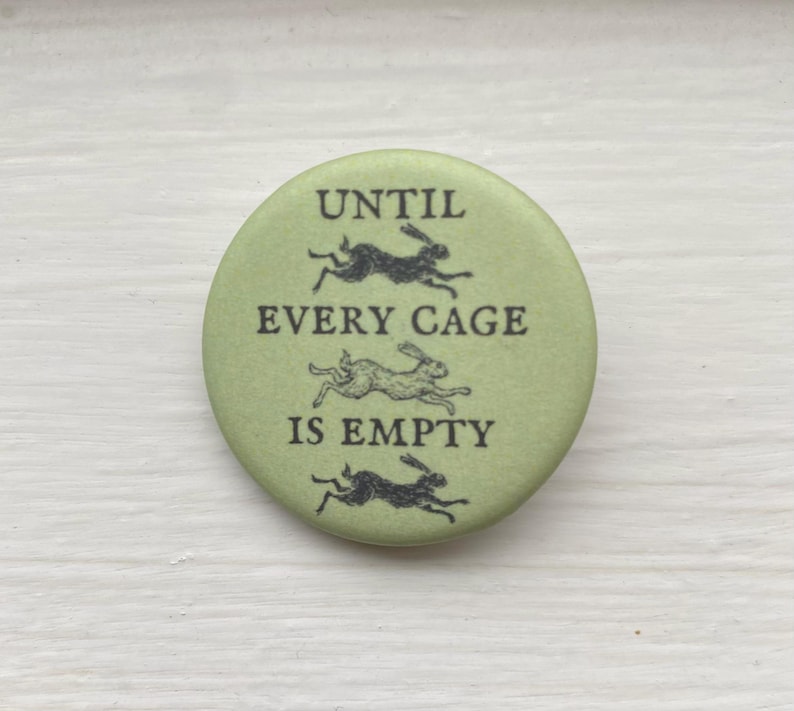 Op de afbeelding: Een groene knop met de tekst "Until every cage is empty" en drie zwarte silhouetten van konijnen die rennen.