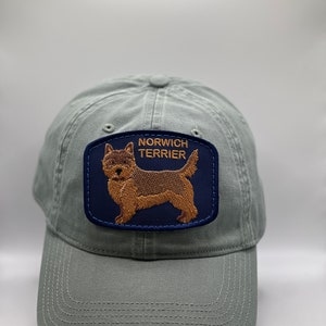 May include: A green baseball cap with a blue and brown embroidered patch that says "Norwich Terrier".