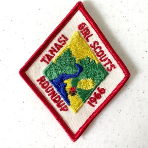 May include: Embroidered Girl Scouts patch with a red border. The patch features the words "Tanasi Roundup" and "Girl Scouts 1966." The center design includes a river, trees, and a yellow and blue background.