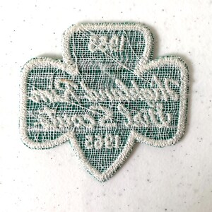 May include: A green and white embroidered Girl Scout trefoil patch. The patch features the words "Girl Scouts" and "3301" in white thread. The patch has a white border and a green mesh background.