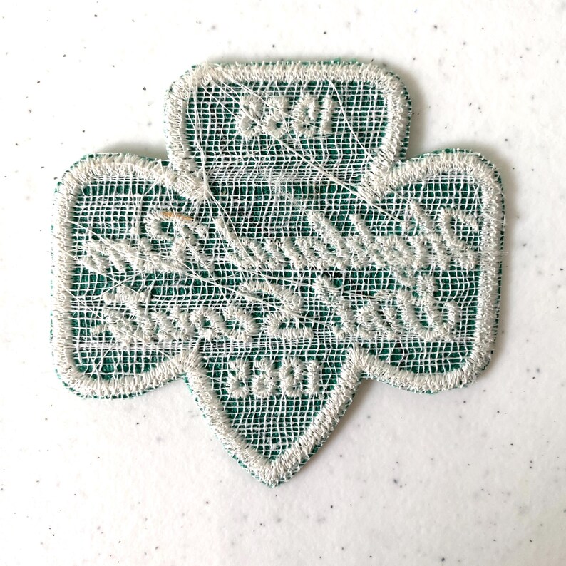 May include: A green and white embroidered Girl Scout trefoil patch. The patch features the words "Girl Scouts" and "3301" in white thread. The patch has a white border and a green mesh background.