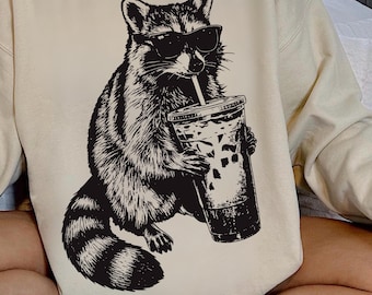 Camiseta divertida de mapache bebiendo café helado, diseño gráfico de meme animal.