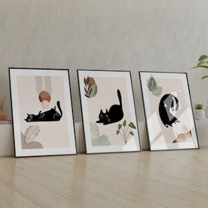 May include: Three framed prints with black silhouettes of cats on a light pink background with green foliage and brown abstract shapes.