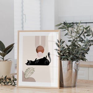 May include: A framed print with a minimalist design featuring a black cat lying down with geometric shapes in shades of brown, pink, and beige.
