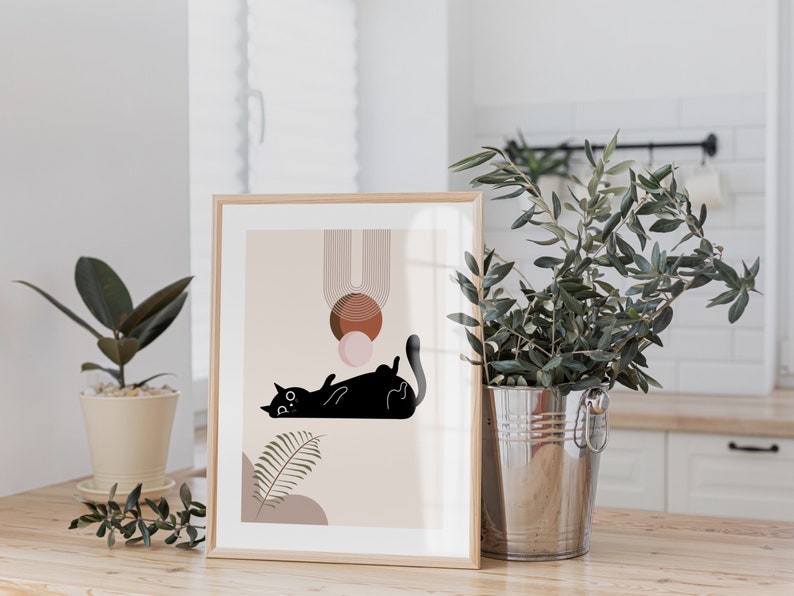 May include: A framed print with a minimalist design featuring a black cat lying down with geometric shapes in shades of brown, pink, and beige.