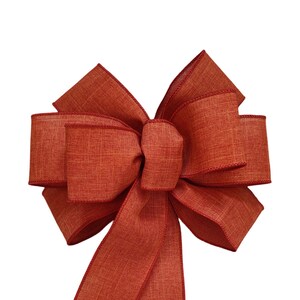 May include: A large, red, burlap bow with two long tails. The bow is tied with a single knot in the center.