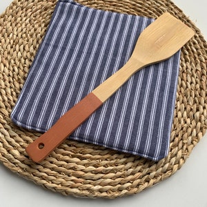 May include: A blue and white striped kitchen pot holder with a wooden spatula with a brown handle.